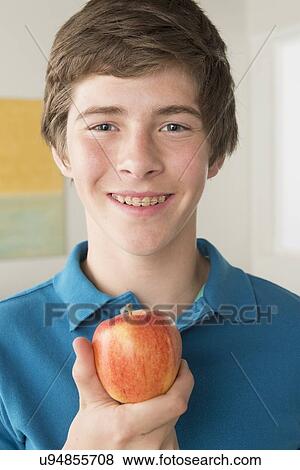 Boy (14-15) holding apple View Large Photo Image Stock Photo - Boy (14-15) holding apple. Fotosearch