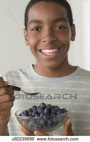 Boy (14-15) holding bowl of black berries View Large Photo Image Stock Photo - Boy (14-15) holding bowl of black berries. Fotosearch