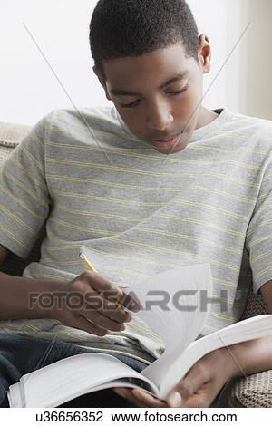 Stock Image - Boy (14-15) studying. Fotosearch