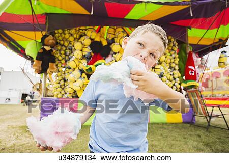 Boy (4-5) eating cotton candy in amusement park View Large Photo Image Picture - Boy (4-5) eating cotton candy in amusement park . Fotosearch