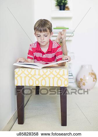 Boy (6-7) lying on bench reading book View Large Photo Image Stock Photo - Boy (6-7) lying on bench reading book. Fotosearch