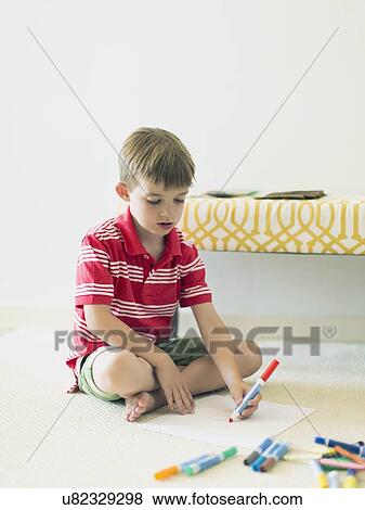 Stock Photo - Boy (6-7) sitting on floor and drawing . Fotosearch