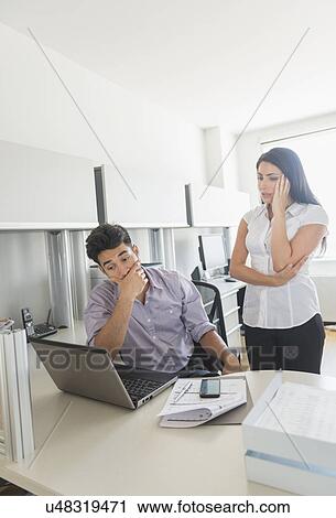 Stock Image - Business man and woman at work in office. Fotosearch