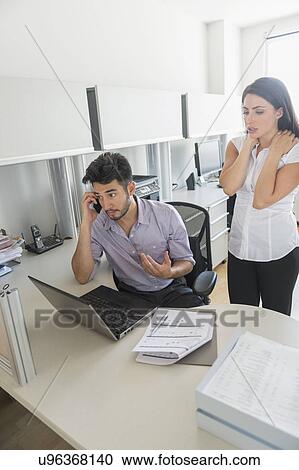 Stock Image - Business man and woman at work in office. Fotosearch
