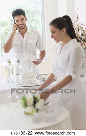 Stock Image - Business owners preparing dining table. Fotosearch