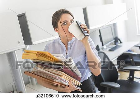 Business woman holding stack of documents and drinking coffee View Large Photo Image Stock Image - Business woman holding stack of documents and drinking coffee. Fotosearch