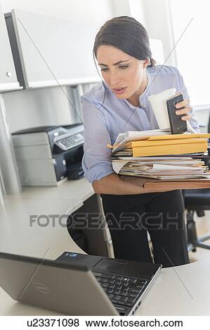 Business woman holding stack of documents and coffee cup View Large Photo Image Stock Photo - Business woman holding stack of documents and coffee cup. Fotosearch