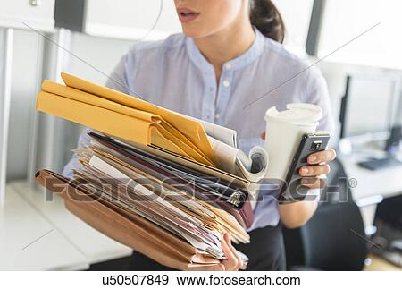 Business woman holding stack of documents in office View Large Photo Image Stock Photo - Business woman holding stack of documents in office. Fotosearch
