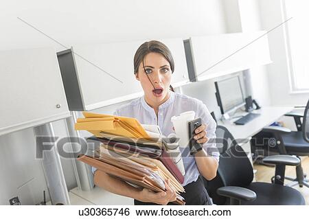 Business woman holding stack of documents in office View Large Photo Image Stock Photograph - Business woman holding stack of documents in office. Fotosearch