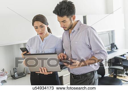 Businessman and businesswoman using technology in office View Large Photo Image Stock Image - Businessman and businesswoman using technology in office. Fotosearch