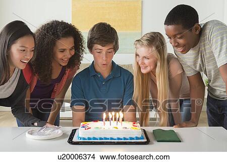 Picture - Children (12-13, 14-15, 16-17) blowing candles on birthday cake. Fotosearch