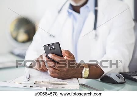 Stock Photo - Close up of doctor's hand holding mobile phone. Fotosearch