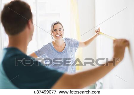 Stock Photo - Couple measuring wall. Fotosearch