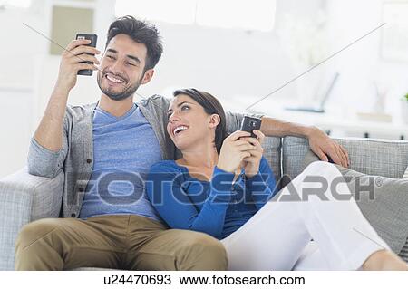 Couple relaxing on sofa with cell phones View Large Photo Image Stock Image - Couple relaxing on sofa with cell phones. Fotosearch