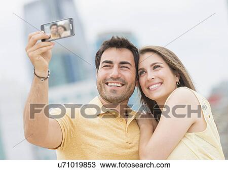 Couple taking self portrait photo with smartphone View Large Photo Image Stock Image - Couple taking self portrait photo with smartphone. Fotosearch