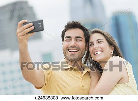 Couple taking self portrait photo with smartphone View Large Photo Image Stock Photo - Couple taking self portrait photo with smartphone. Fotosearch