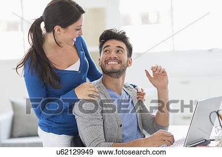 Stock Photo - Couple using laptop at home. Fotosearch