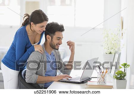 Stock Photograph - Couple using laptop at home. Fotosearch