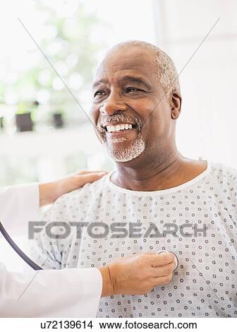 Doctor using stethoscope on smiling patient View Large Photo Image Picture - Doctor using stethoscope on smiling patient. Fotosearch