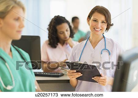 Stock Image - Doctors and nurses working at desks in hospital. Fotosearch