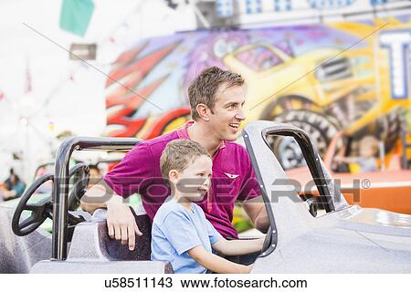 Father with son (4-5) driving toy car in amusement park View Large Photo Image Stock Image - Father with son (4-5) driving toy car in amusement park. Fotosearch