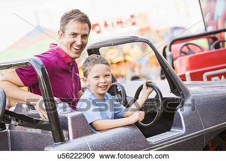 Stock Photo - Father with son (4-5) driving toy car in amusement park. Fotosearch