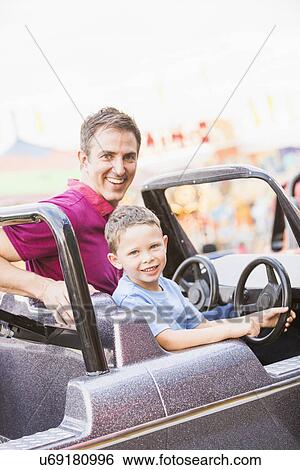 Father with son (4-5) driving toy car in amusement park View Large Photo Image Stock Photograph - Father with son (4-5) driving toy car in amusement park. Fotosearch