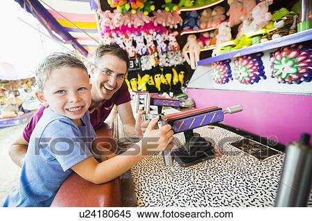 Father with son (4-5) playing with water gun in amusement park View Large Photo Image Stock Photography - Father with son (4-5) playing with water gun in amusement park. Fotosearch