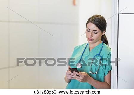 Stock Image - Female doctor text messaging. Fotosearch