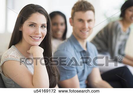 Stock Image - Friends sitting on sofa. Fotosearch