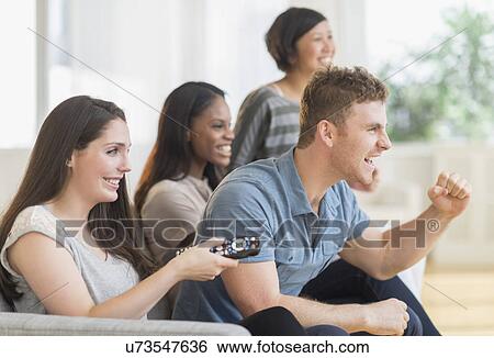 Friends watching tv on sofa View Large Photo Image Stock Photograph - Friends watching tv on sofa. Fotosearch