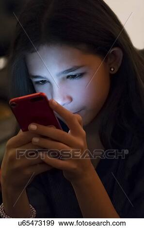 Stock Photo - Girl (12-13) texting on mobile phone at night. Fotosearch