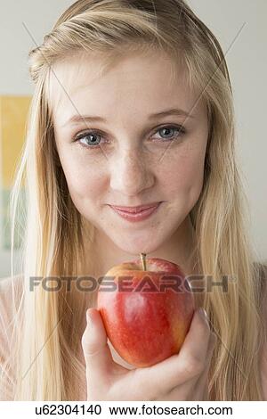 Stock Image - Girl (14-15) holding apple. Fotosearch