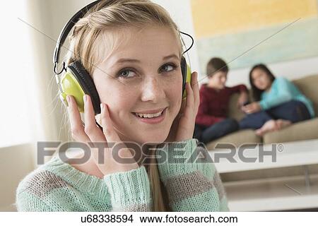 Picture - Girl (14-15) listening to music wearing headphones. Fotosearch