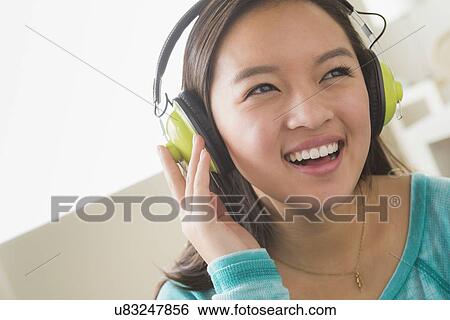 Girl (16-17) listening to music wearing headphones View Large Photo Image Stock Photograph - Girl (16-17) listening to music wearing headphones. Fotosearch