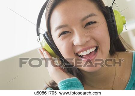Stock Photography - Girl (16-17) listening to music wearing headphones. Fotosearch