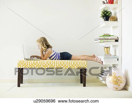 Girl (4-5) lying on bench using laptop View Large Photo Image Stock Photograph - Girl (4-5) lying on bench using laptop. Fotosearch
