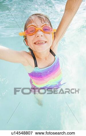 Stock Photo - Girl (8-9) playing in swimming pool. Fotosearch