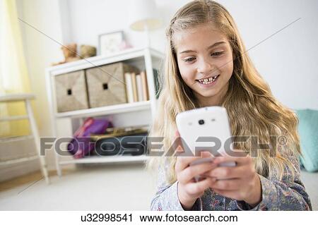 Stock Image - Girl (8-9) using mobile phone. Fotosearch