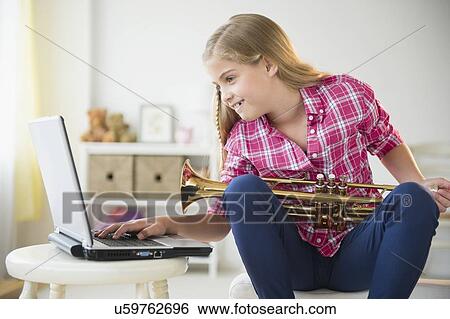 Girl (8-9) with trumpet using laptop View Large Photo Image Stock Photograph - Girl (8-9) with trumpet using laptop. Fotosearch