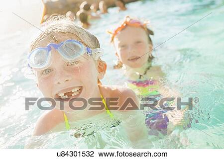 Stock Image - Girlfriends (4-5, 8-9) playing in swimming pool. Fotosearch