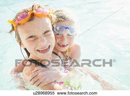 Stock Photography - Girlfriends (4-5, 8-9) playing in swimming pool. Fotosearch