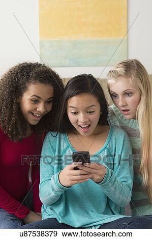 Stock Photo - Girls (12-13, 14-15, 16-17) playing with smartphone. Fotosearch