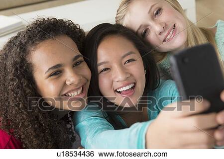 Stock Photograph - Girls (12-13, 14-15, 16-17) playing with smartphone. Fotosearch