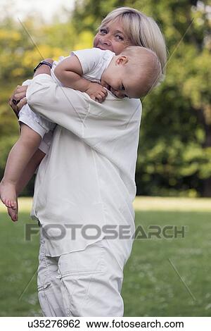 Grandmother carrying her granddaughter (12-17 months) on shoulder View Large Photo Image Stock Image - Grandmother carrying her granddaughter (12-17 months) on shoulder. Fotosearch
