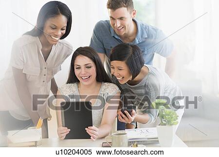Stock Photography - Group of young friends using digital tablet. Fotosearch