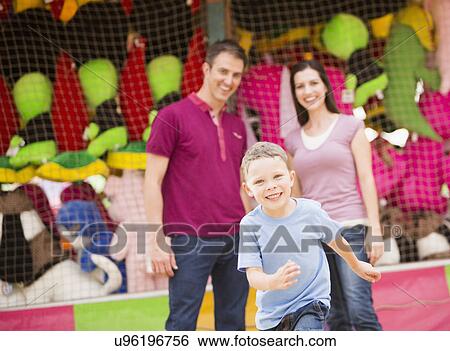 Stock Photograph - Happy Family and son (4-5) having fun in amusement park. Fotosearch