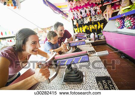 Stock Photography - Happy Family with son (4-5) playing with water gun in amusement park. Fotosearch