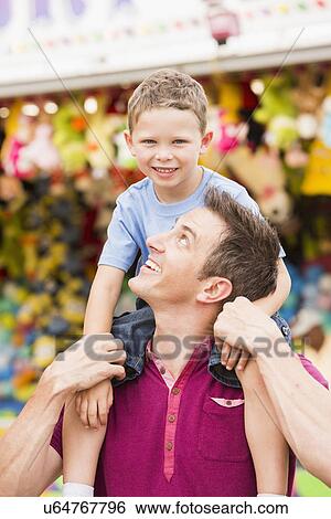 Stock Photograph - Happy father with son (4-5) in amusement park. Fotosearch