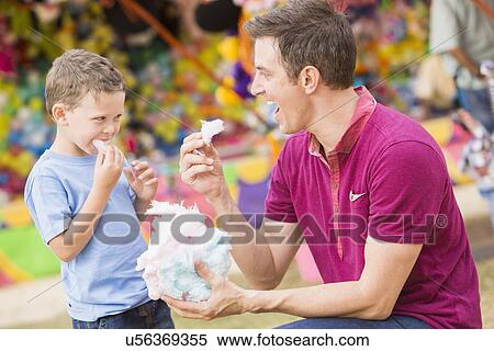 Happy father with son (4-5) in amusement park eating cotton candy View Large Photo Image Stock Photography - Happy father with son (4-5) in amusement park eating cotton candy. Fotosearch